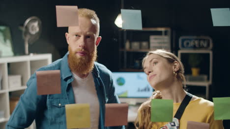 Bearded-man-and-beautiful-woman-discussing-business-ideas-in-hipster-office