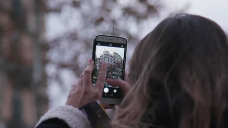 vista trasera de una mujer elegante tomando fotografías del famoso edificio con teléfono