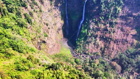 steep drone reveal unveils the majestic twin streams of tad fane waterfall plunging into a deep gorge amid lush rainforest on the bolaven plateau in champasak province, southern laos