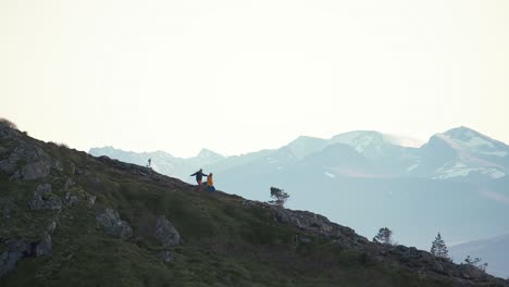 two persons walking down a steep hill, surrounded by mist and mountains