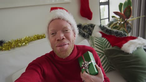 Happy-albino-african-american-man-wearing-santa-hat-making-video-call-at-christmas