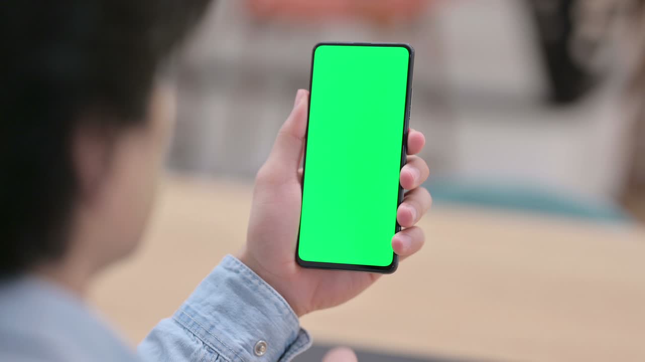vista trasera, hombre usando teléfono inteligente con pantalla clave de croma verde