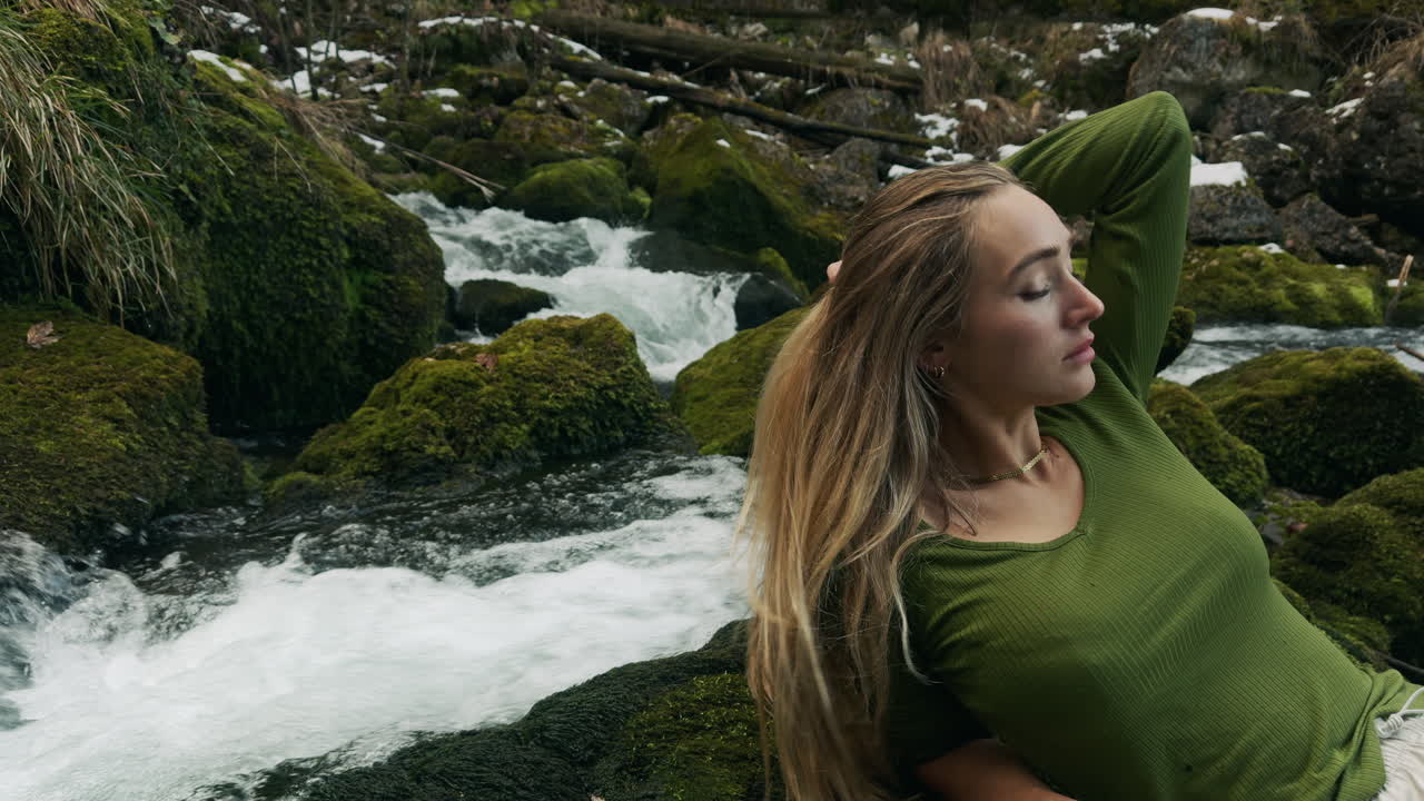 donna che si rilassa vicino a un ruscello di montagna