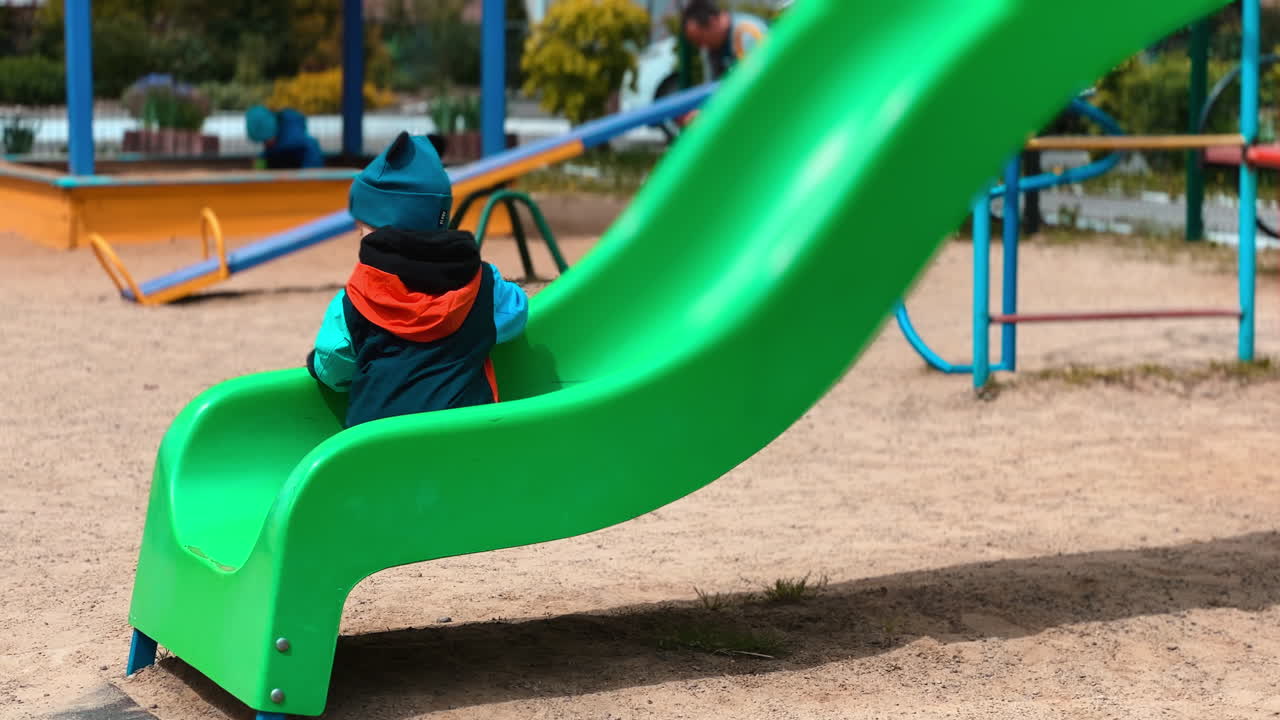 Caucasian toddler climbs onto the slide on the playground. Little boy tries to go up by the slide.