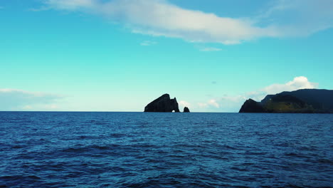 cruising towards piercy island , popularly known as the hole in the rock, located in north island of new zealand - low-level, wide shot