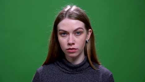 young blonde model watching calmly and intently into camera isolated on green chromakey background.