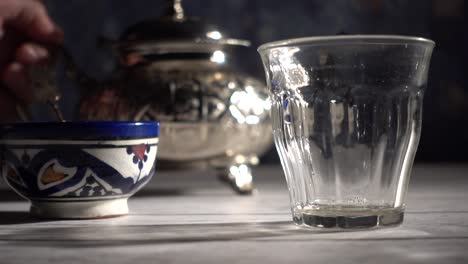 Slow-motion-extreme-closeup-of-tea-pouring-into-a-glass-on-a-dark-blue-background