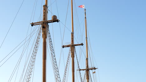 static view of vintage ship sail mast, flag and ladders under blue sky