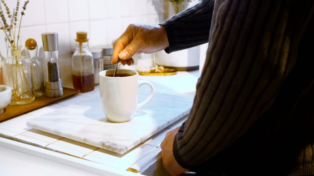 Man stirring coffee with spoon in kitchen 4k