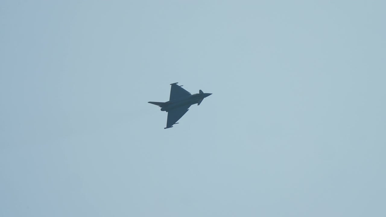 Fighter jet banking against clear blue sky