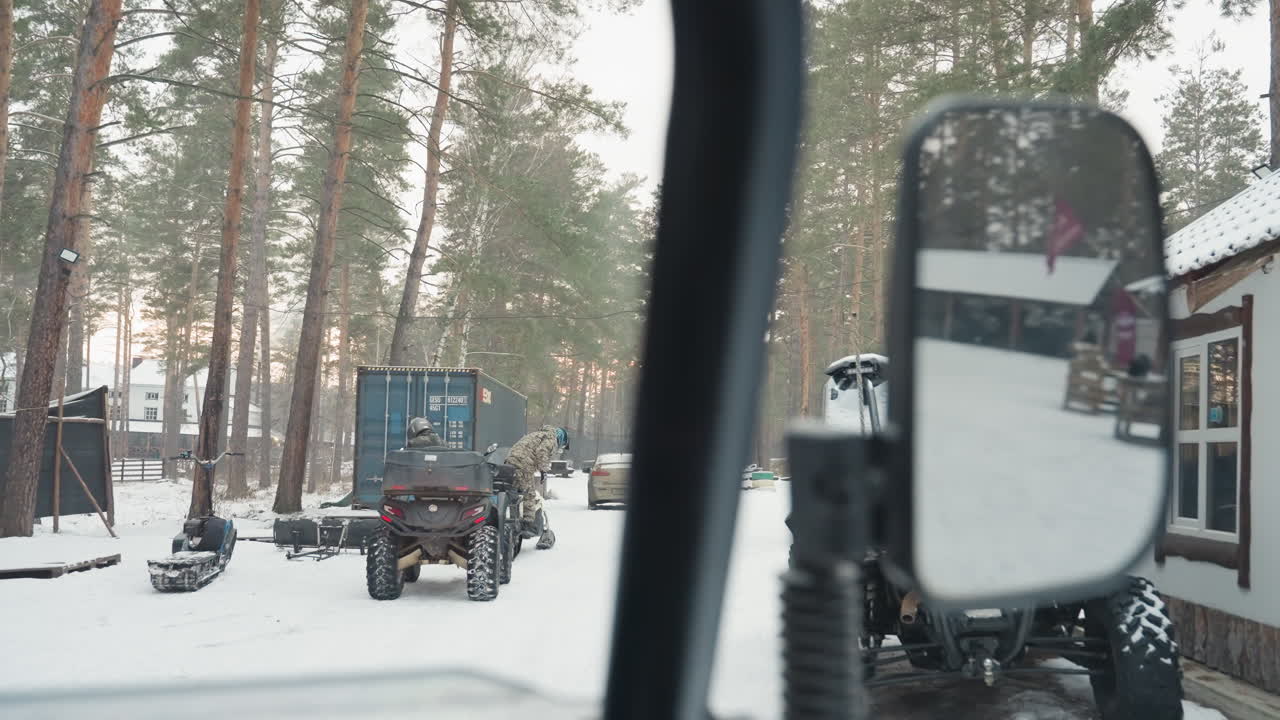 Snowy camp convoy arrival atv mirror closeup drivers park near cabins, windshield and mirror reflections reveal people moving between vehicles, trailers and gear, dusk winter light, lively gathering