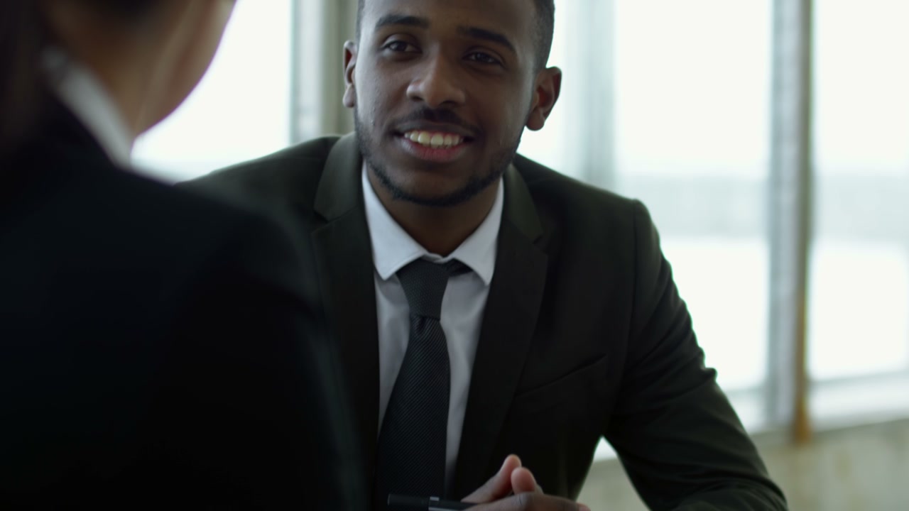 Close Up View Of Afroamerican Businessman Ina Meeting With Coworkers Sitting At A Table, While Discussing Details Of A Project