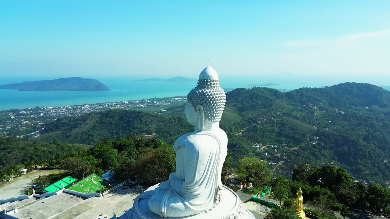 Aerial view of the iconic Big Buddha statue in Phuket, Thailand, overlooking lush green hills and the turquoise Andaman Sea.