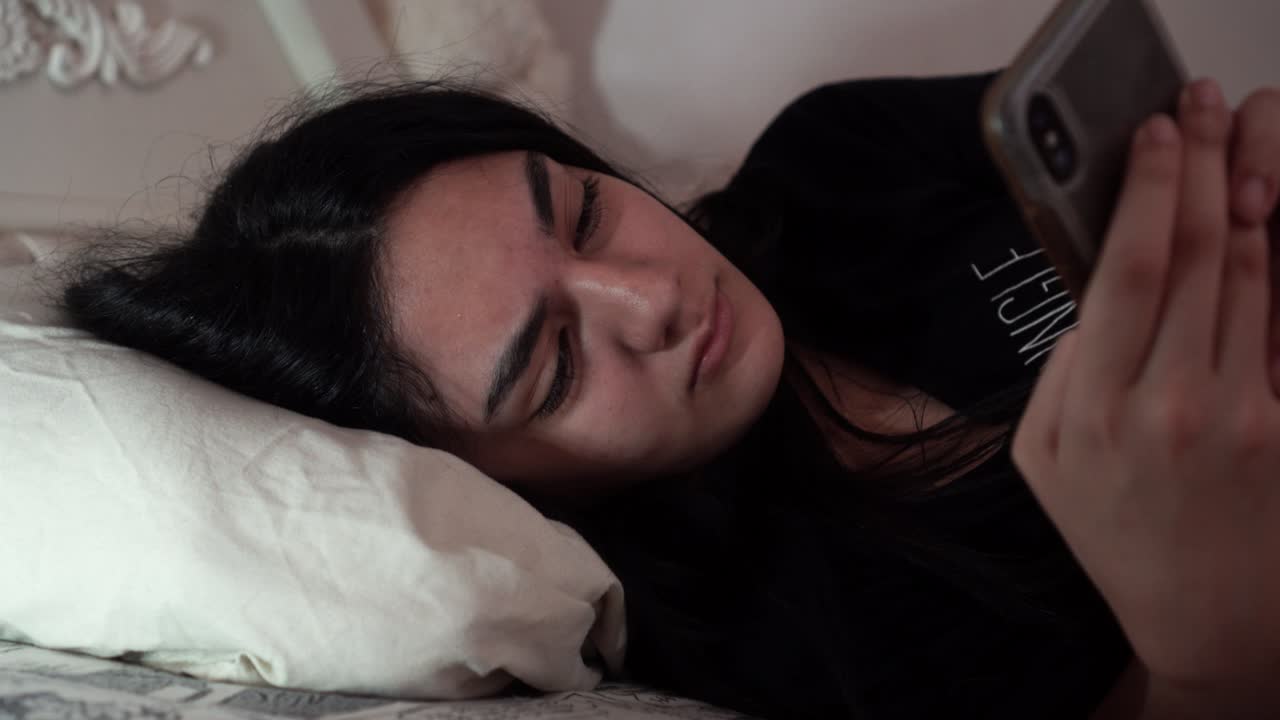 chica enojada enviando mensajes de texto en su teléfono en la cama