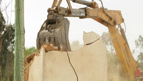 heavy machinery demolishing concrete wall of a house