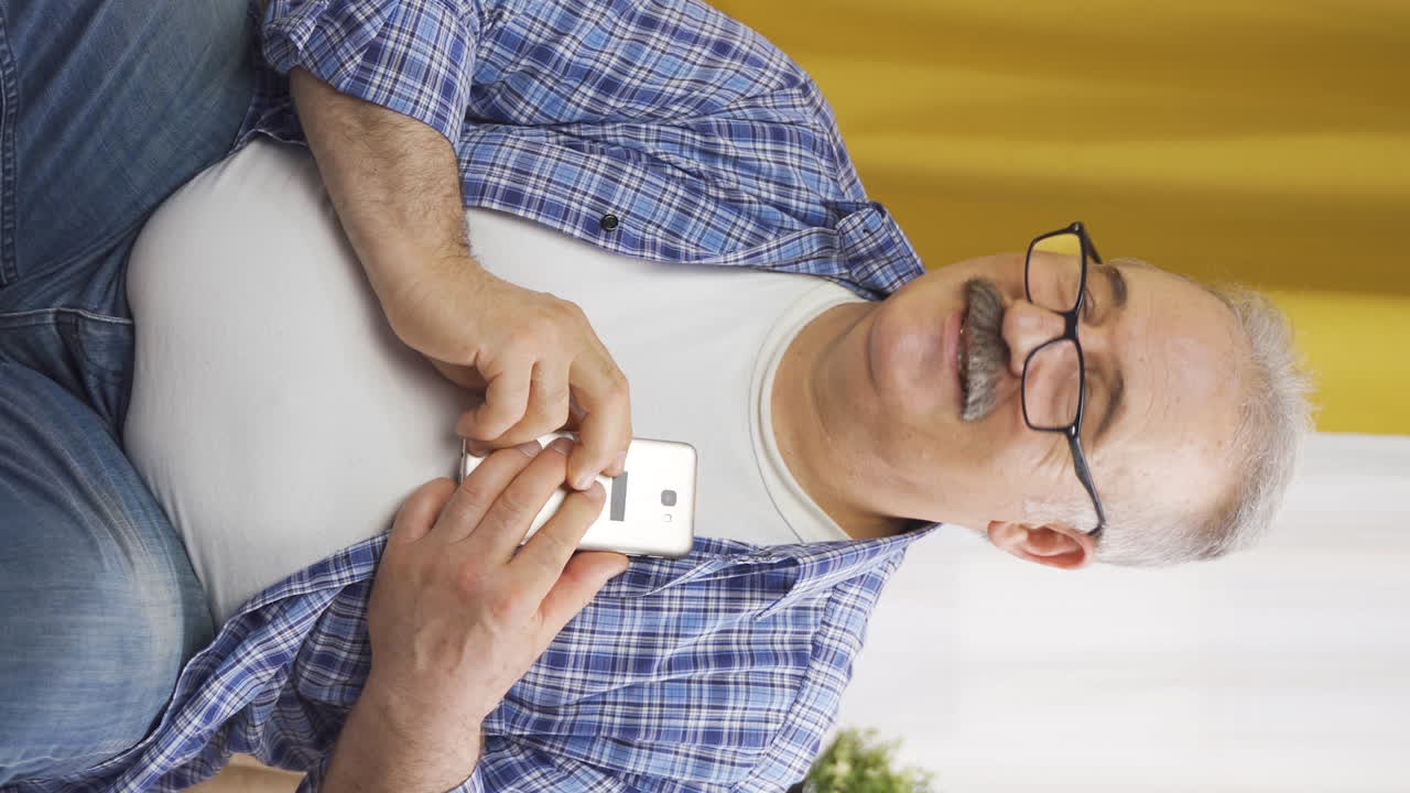 вертикальное видео старика, который с радостью подносит телефон к сердцу.