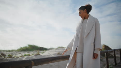 mujer melancólica caminando por la playa en el fin de semana de otoño. cabello negro molesto duda femenina