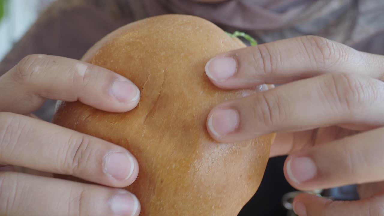 Close up of a person holding a hamburger