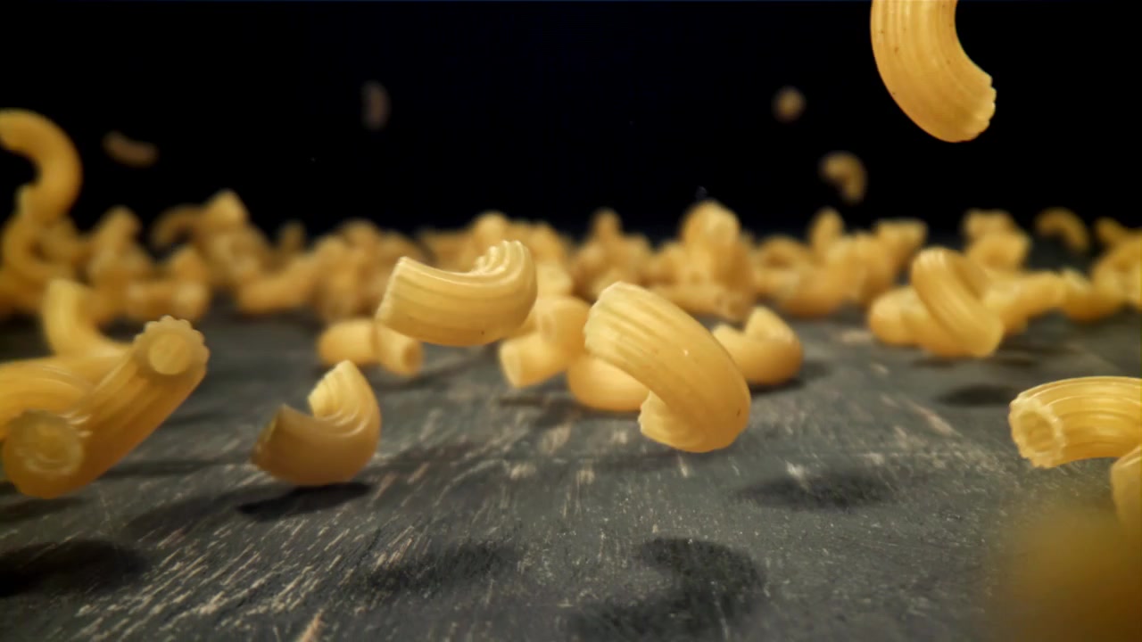 Maccheroni crudi che cadono su una superficie scura e testurizzata
