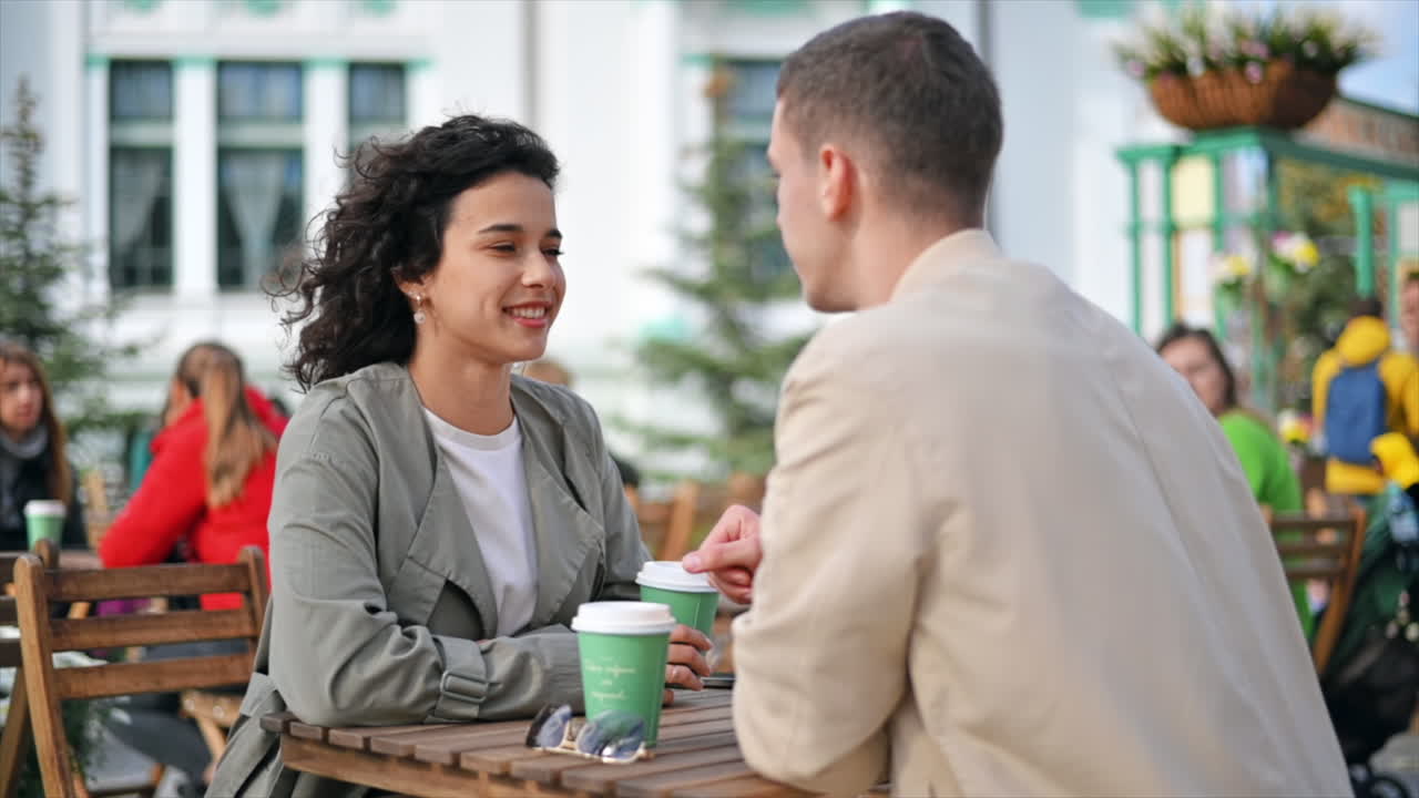 A happy couple outdoors near a cafe. Looking at each other, smiling and talking, coffee. Autumn atmosphere. Slow motion