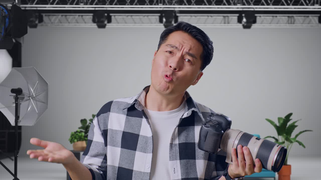 Man expressing confusion while holding a camera in a photography studio