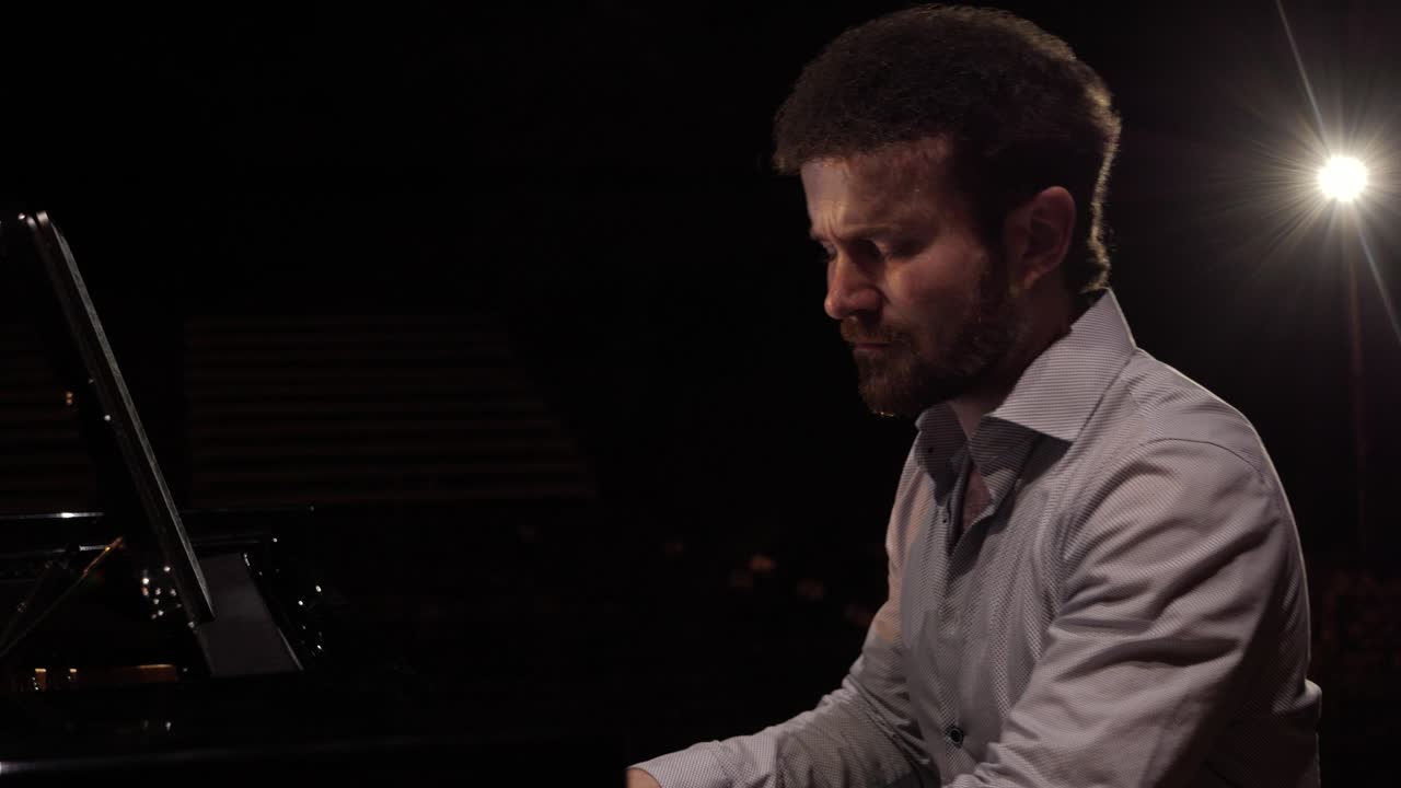 pianista masculino tocando en la luz en un piano de cola