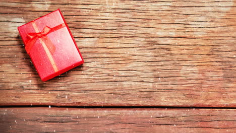 weihnachtsgeschenk auf holz kombiniert mit fallendem schnee
