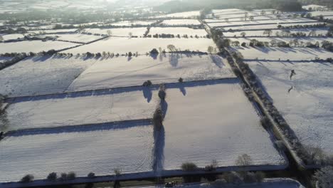 Frío-Nevado-Invierno-Británico-Patchwork-Tierras-De-Cultivo-Campo-Rural-Escena-Aéreo-Tiro-Lento-Hacia-Adelante-Al-Amanecer