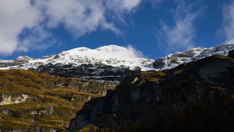 Zeitrafferaufnahme-Von-Fliegenden-Wolken-Vor-Blauem-Himmel-über-Schneebedeckten-Bergen-Im-Sonnenlicht