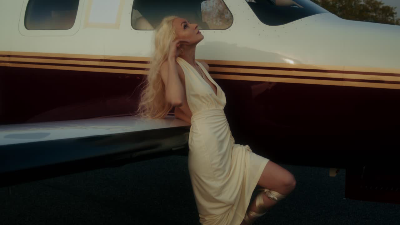 Woman in a cream dress by a private jet
