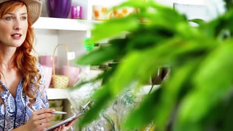 Female-florist-noting-on-clipboard-at-flower-shop