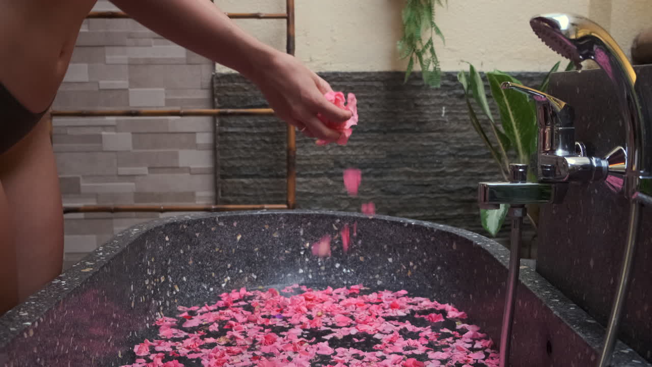 Woman Adding Rose Petals to a Spa Bath