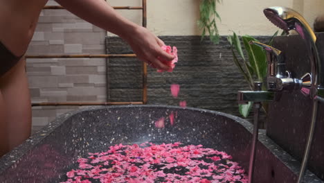 una mujer añadiendo pétalos de rosa a un baño de spa