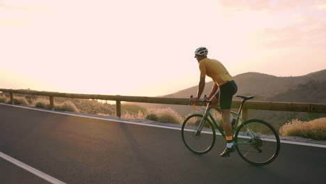 En-Cámara-Lenta,-Subiendo-En-Bicicleta-Por-Una-Montaña-Serpenteante,-El-Atleta-Contempla-La-Pintoresca-Vista-De-La-Isla,-Que-Refleja-El-Compromiso-Con-Un-Estilo-De-Vida-Saludable.