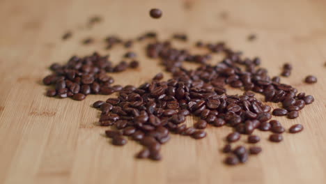 coffee beans dropping into pile on wooden surface in slow motion