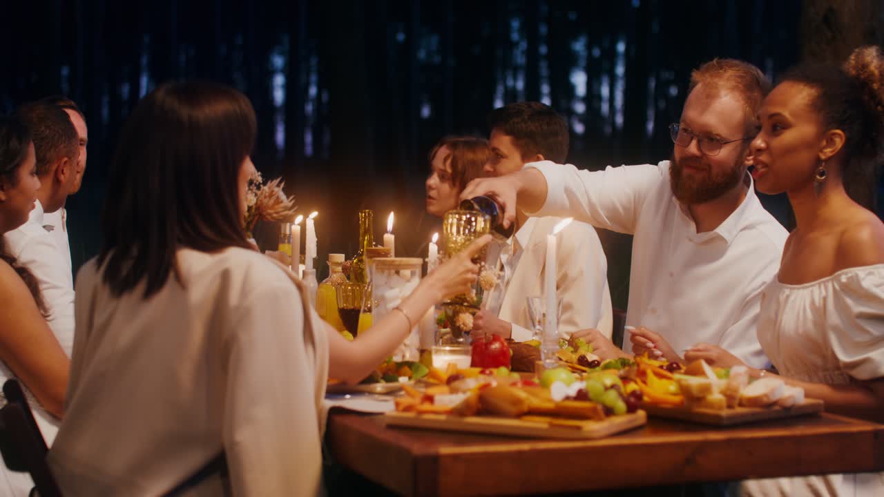 amigos desfrutando de um jantar em uma floresta à noite