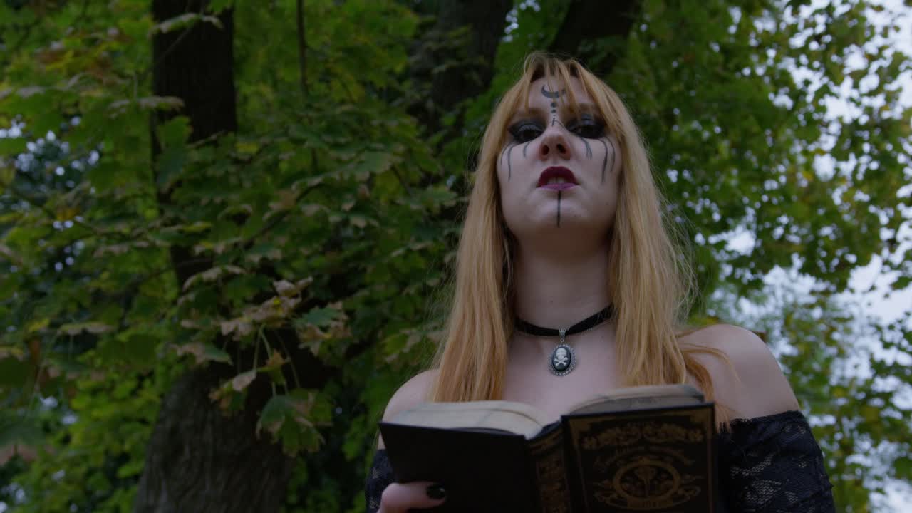 Beautiful Witch smiling in an evil way to the camera and turning around in the cemetery, slow motion Close up