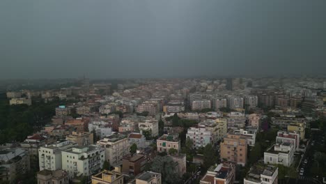 Aerial-drone-shot-over-residential-buildings-with-dark-clouds-and-lightning-striking-over-the-city-of-Rome,-in-Italy