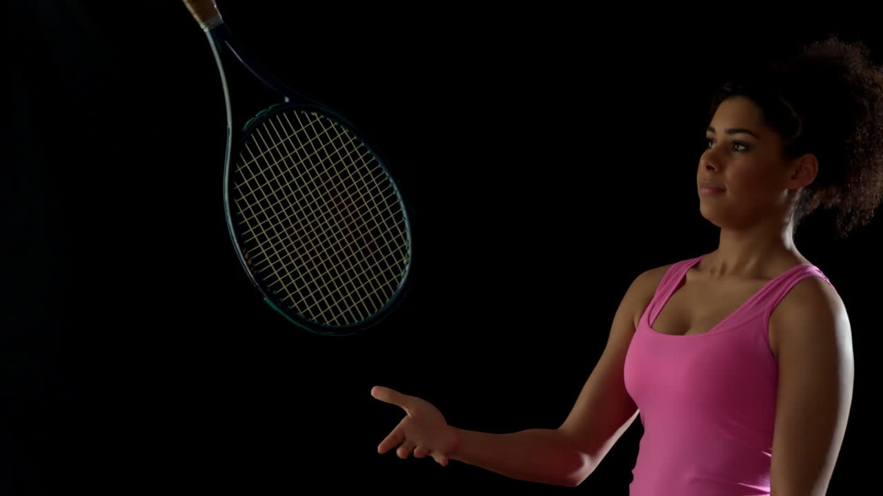 Fit woman in pink tossing a tennis racket