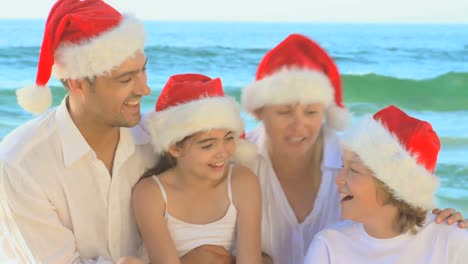 happy family wearing christmas hats and singing on a beach