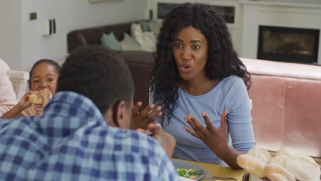 happy african american mother talking and eating lunch with family at home