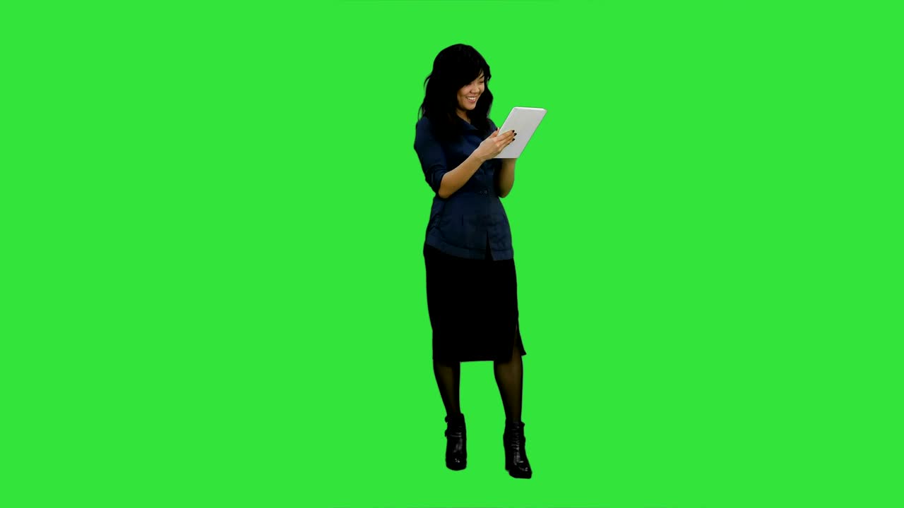 Giovane donna asiatica che usa un tablet digitale e sorride su sfondo Chroma Key.