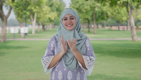 happy muslim woman clapping and appreciating in park