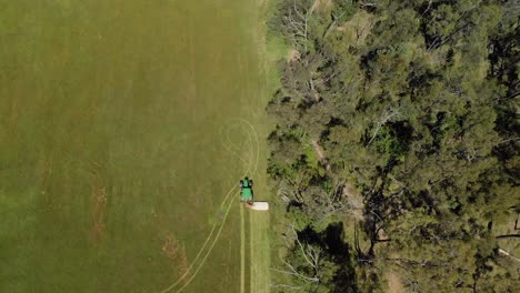 Una-Vista-Aérea-A-Vista-De-Pájaro-De-Un-Tractor-Cortando-Pasto-Seco-Junto-A-Matorrales-En-Las-Zonas-Rurales-De-Australia