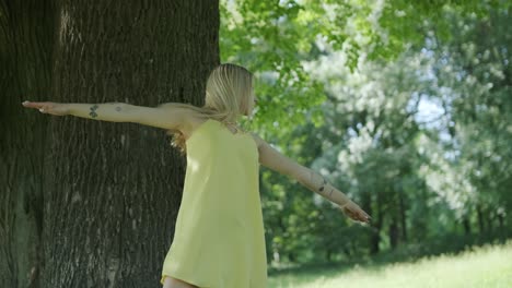 feliz joven hermosa bailando de libertad en el parque de verano con árboles en el fondo.