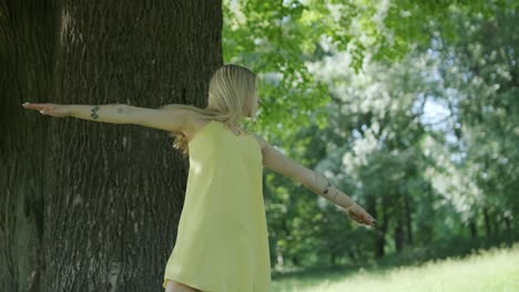 happy beautiful young girl dancing of freedom in summer park with trees in the background.