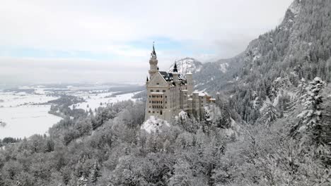 Drohne-Fliegt-Im-Winter-In-Richtung-Schloss-Neuschwanstein-In-Füssen-In-Der-Nähe-Von-Bäumen