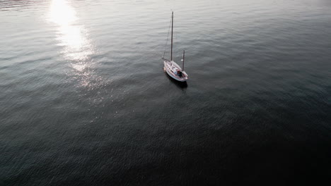 Aerial-video-orbit-of-a-moored-sailboat-with-a-noticeable-sun-glare,-warwick,-ri