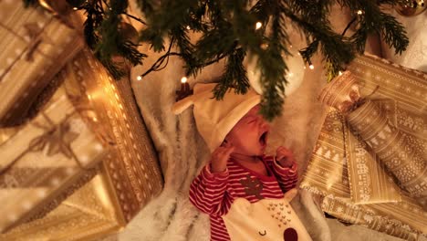 cute newborn baby boy crying under the christmas tree wearing adorable reindeer clothes