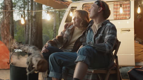 Young-Man-and-Woman-Chatting-by-Campfire-in-Evening